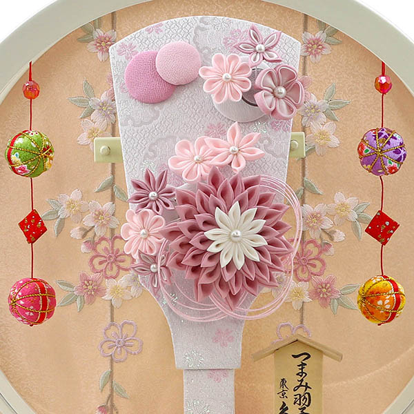 久月　 羽子板　つまみ細工 髪飾り付き 羽子板 桃 白塗り 鞠二連つるし付き 円形 丸型アクリルケース　詳細画像